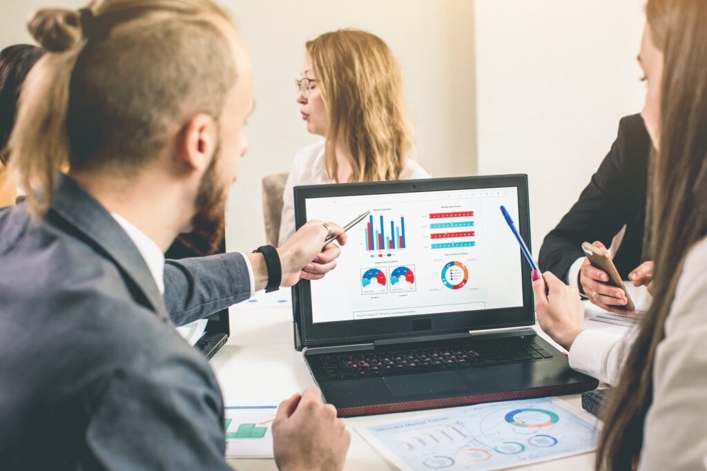 Business professionals. Group of young confident business people analyzing data using computer while